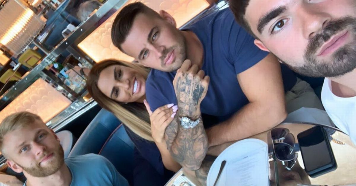 Katie Price affectionately hangs off Carl Woods as they join male friends