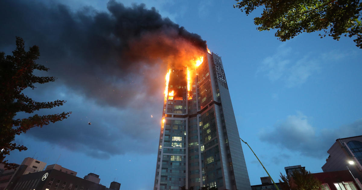 Roaring fire atop high-rise apartment building injures scores