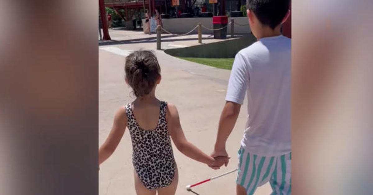 Sister helps brother, who is blind, go down waterslide