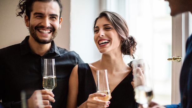 Happy man and woman holding champagne flutes during dinner party at home